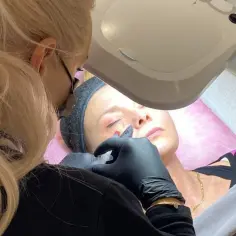 Zabieg z użyciem fibryny bogatopłytkowej. Kosmetolog aplikuje preparat pod oczy pacjentki.