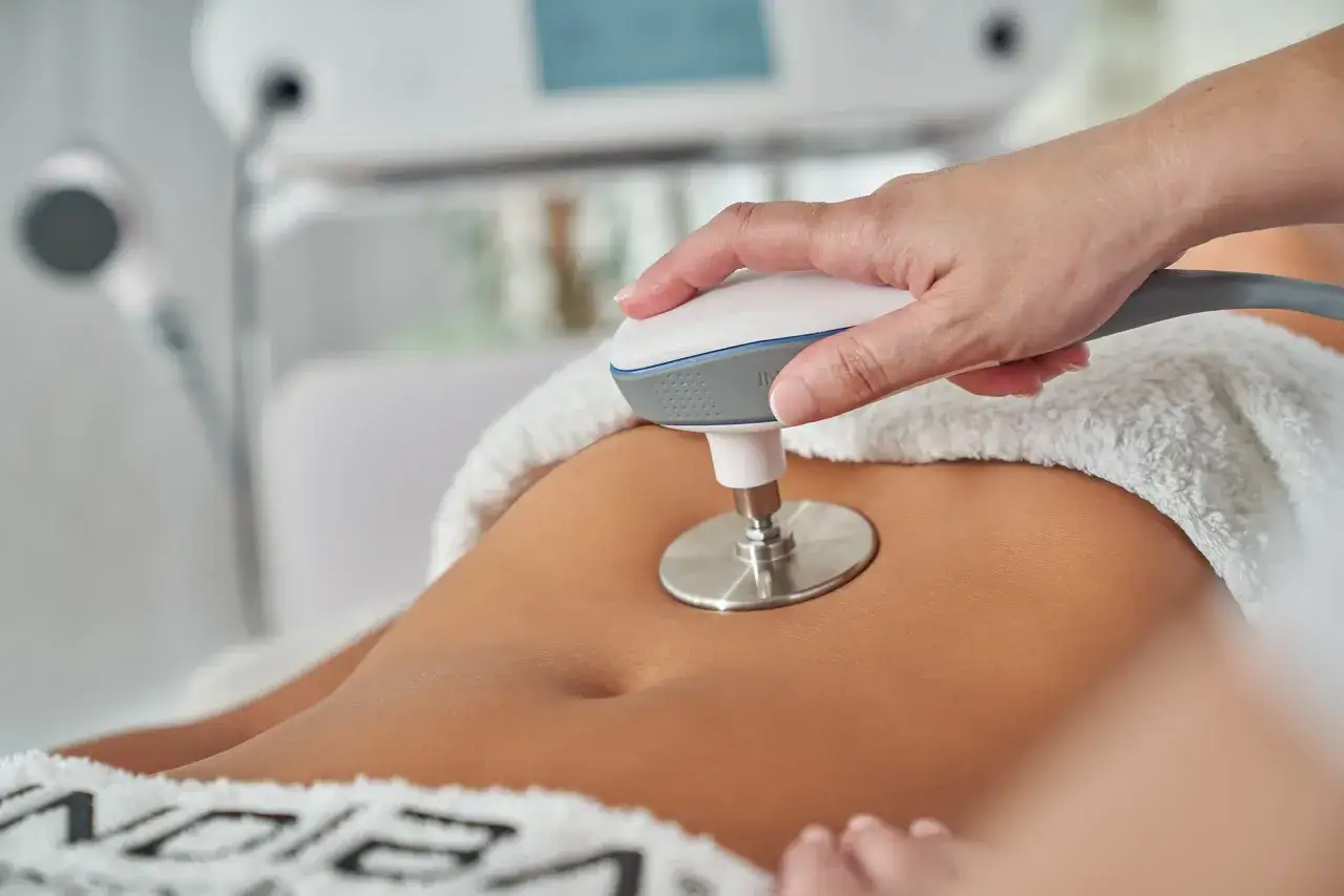 Zabieg indiba za i przeciw: dłoń terapeuty trzymająca głowicę urządzenia nad brzuchem pacjentki.